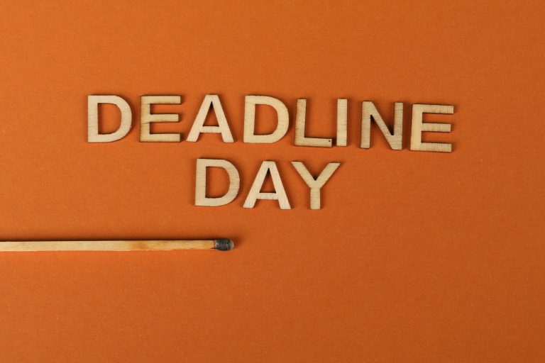 Conceptual image of a deadline with wooden letters and burnt matchstick on orange background.